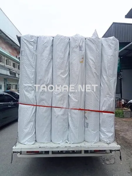 ม้วนตาข่ายพลาสติก สูงพิเศษ 1.8 เมตร ที่มีกระสอบพลาสติกสีขาว ห่ออยู่ วางตั้งเรียงกันบนรถบรรทุก 4 ล้อ